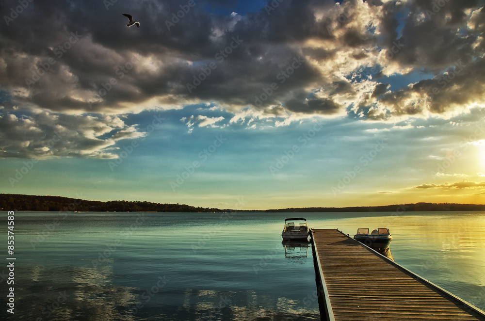 Fototapeta premium Motor boats moored on a jetty on Lake Macquarie, Australia at sunset