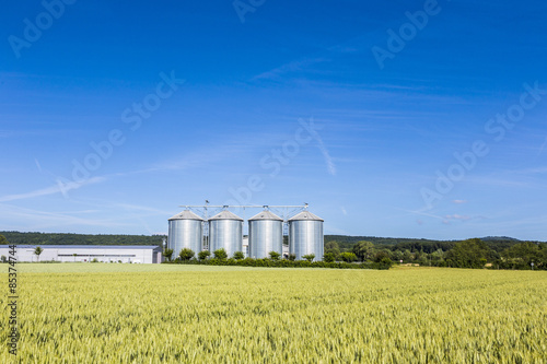 four silver silos in field under bright sky © travelview