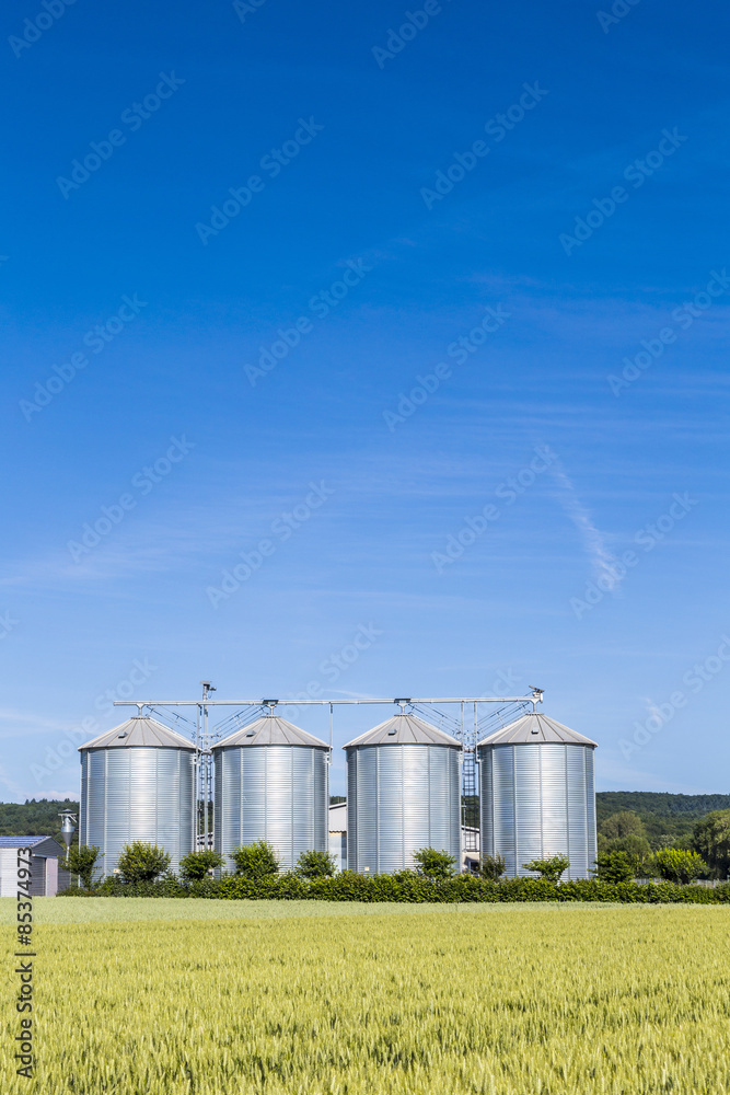 four silver silos in field under bright sky four silver silos in field under bright sky