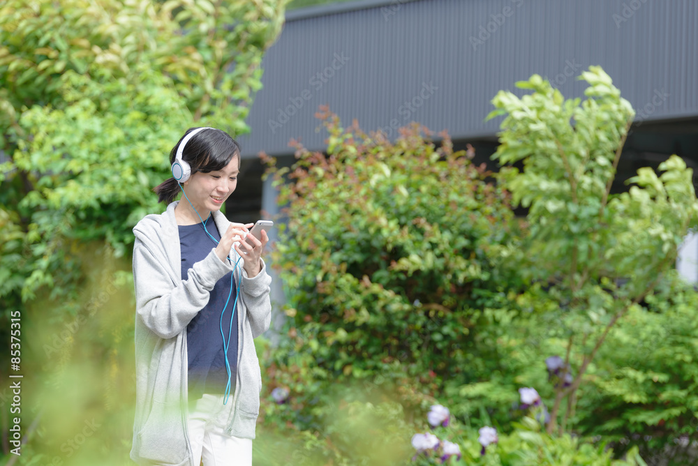 スマートフォンで音楽を聞きながら歩く女性 スマートフォンで音楽を聞きながら歩く女性