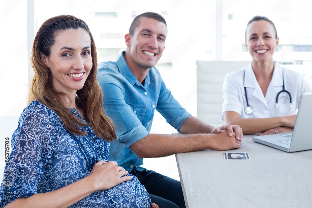 Obraz premium Doctor and future parents smiling at camera