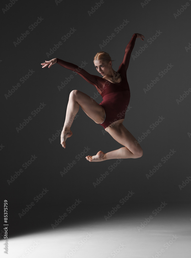 Young beautiful modern style dancer jumping on a studio