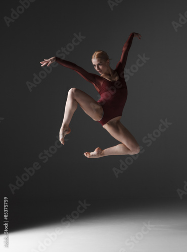 Young beautiful modern style dancer jumping on a studio