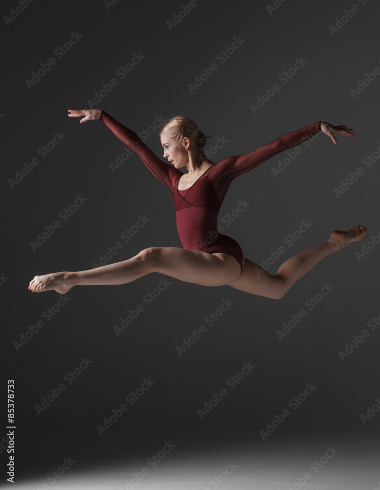 Fototapeta premium Young beautiful modern style dancer jumping on a studio