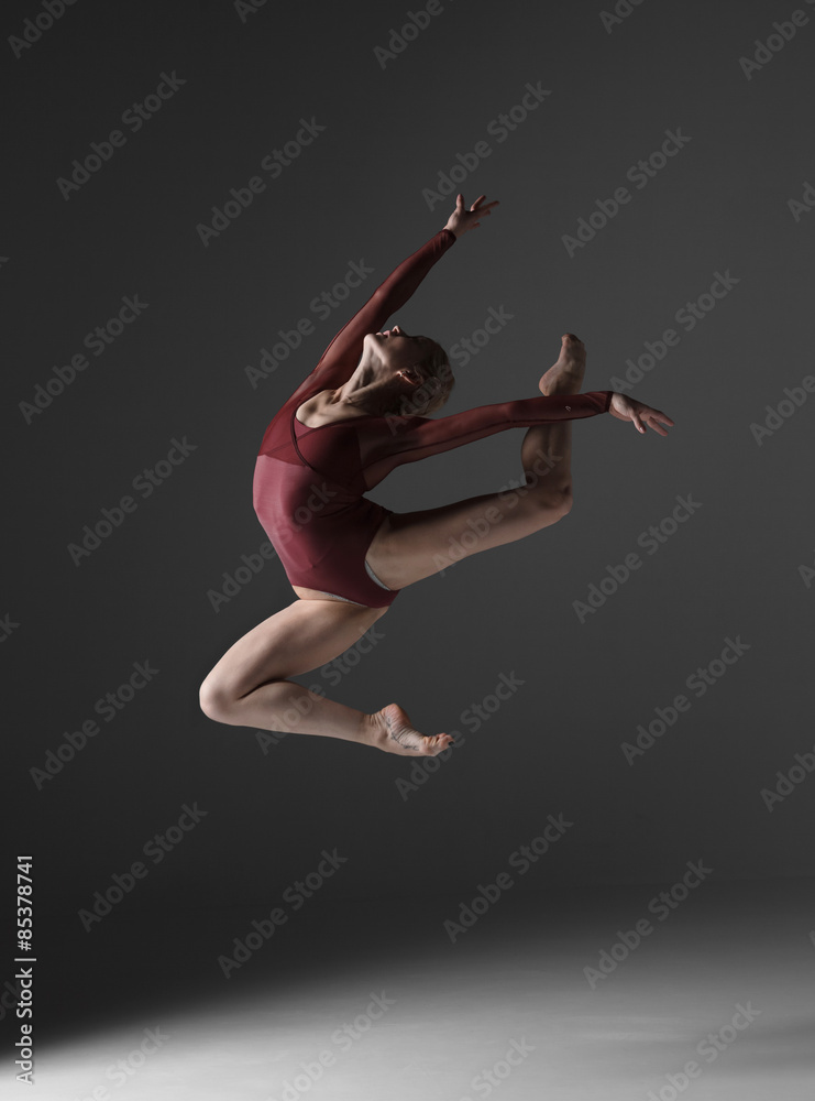 Fototapeta premium Young beautiful modern style dancer jumping on a studio