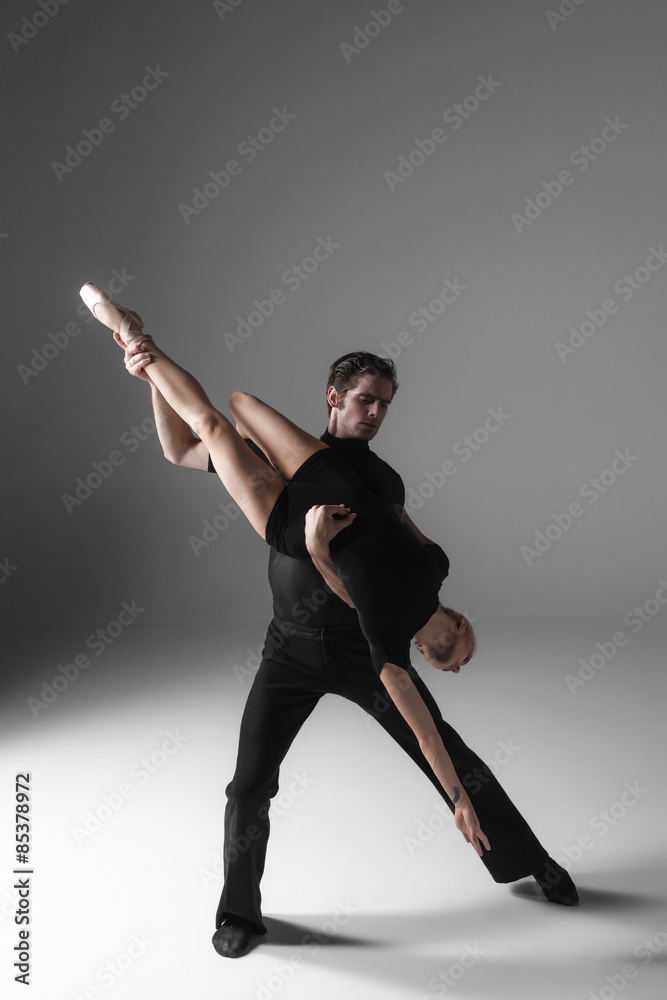 Obraz premium two young modern ballet dancers on gray studio background