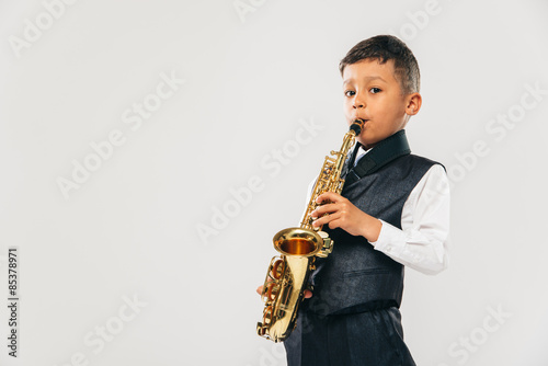 six years old boy plays saxophone at studio