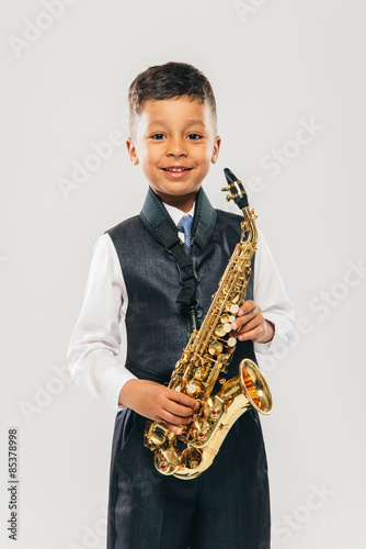 six years old boy plays saxophone at studio