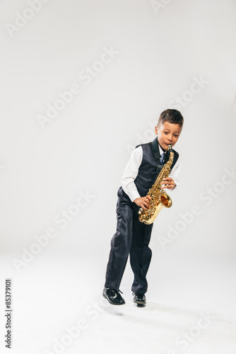 six years old boy plays saxophone at studio