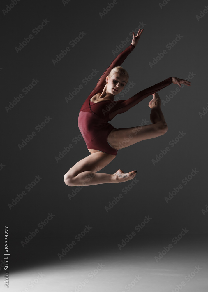 Fototapeta premium Young beautiful modern style dancer jumping on a studio