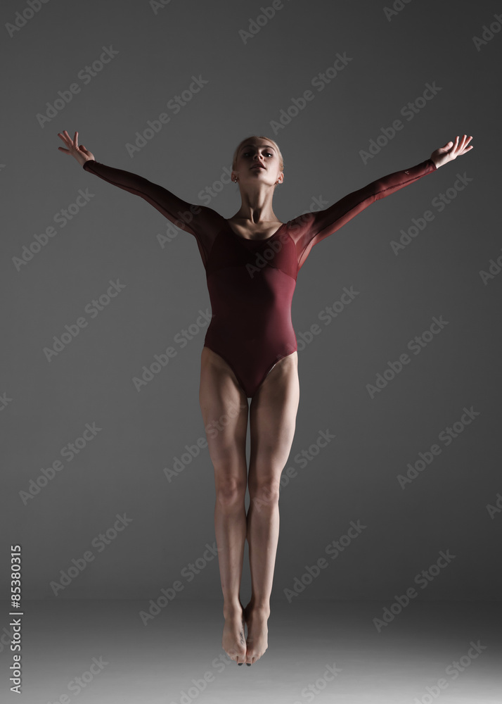 Young beautiful modern style dancer jumping on a studio