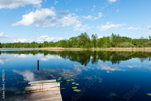 White clouds on the blue sky over blue lake with boats and board