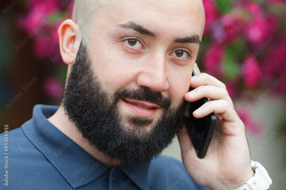 Bearded man talking on the phone mobile flowers background Bearded man talking on the phone mobile flowers background