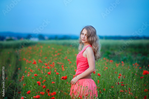 Happy girl in a red dress on poppy field