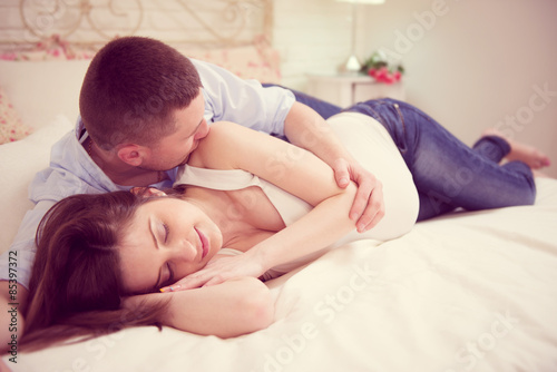 Happy young pregnant couple in bedroom