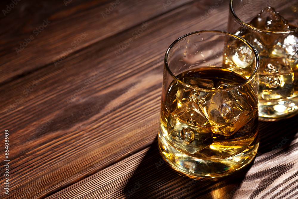 Glasses of whiskey with ice on wood Glasses of whiskey with ice on wood