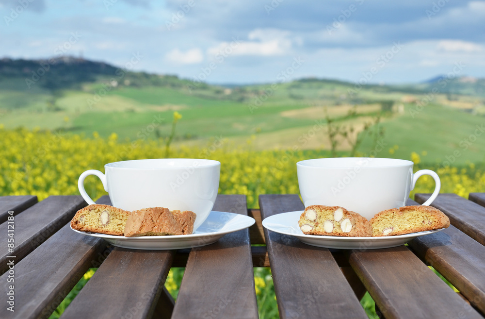 Obraz premium Two coffee cups and cantuccini on the wooden table against Tusca