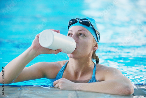 swimmer resting in a pool drinking bottled water