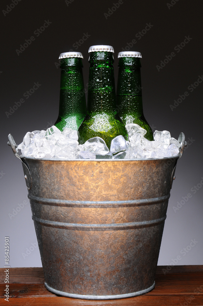 Ice bucket with three bottles of beer on a wet wood bar counter top