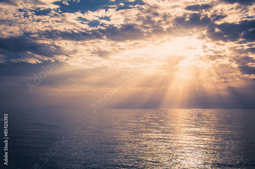 Beautiful sunset over the sea.
Sunbeams are shining through the clouds.