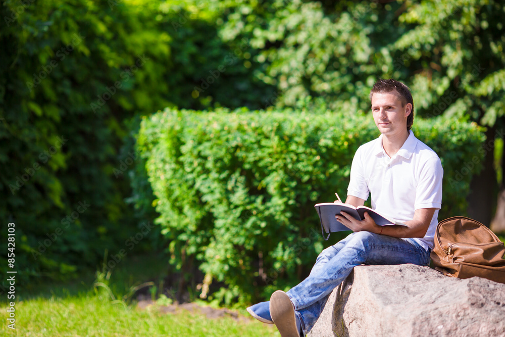 Young man studying for college exam in park outside Young man studying for college exam in park outside