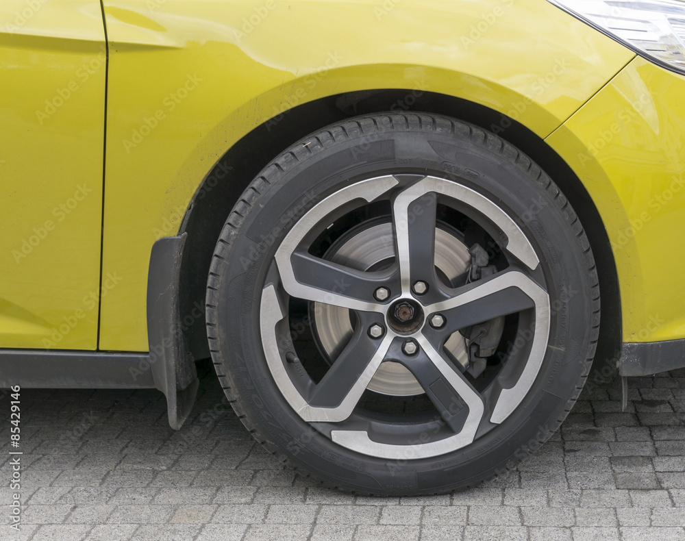 Yellow car closeup - front wheel with light alloy rim Yellow car closeup - front wheel with light alloy rim