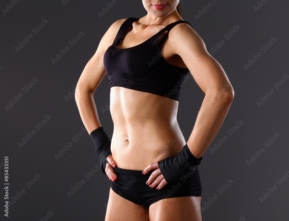 Muscular young woman standing on gray background Muscular young woman standing on gray background