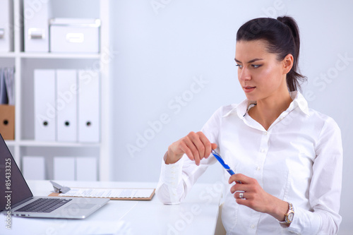 Attractive businesswoman sitting on a desk with laptop in the