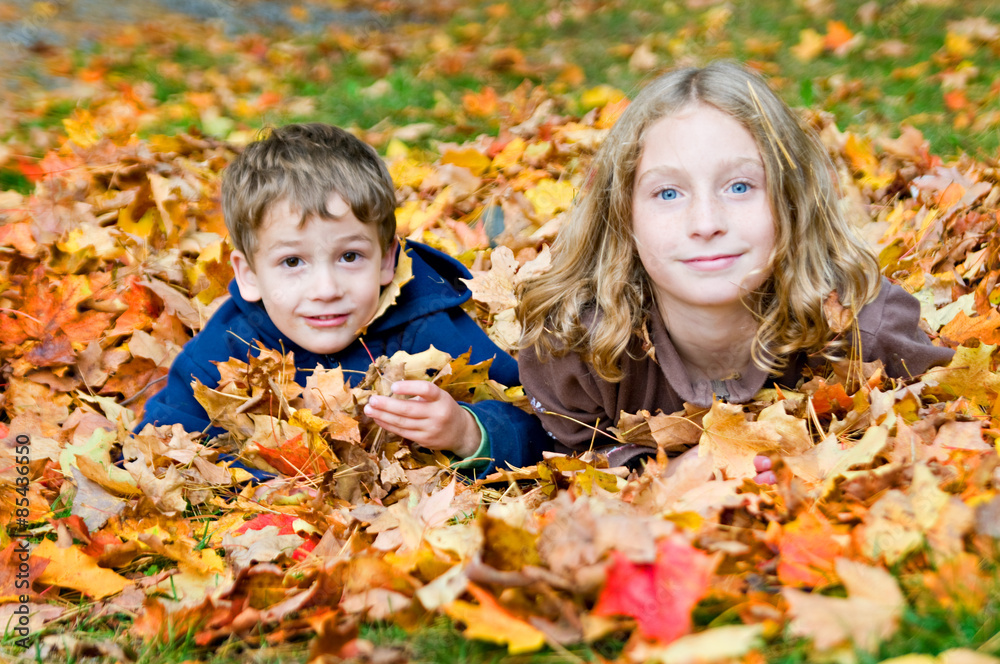 boy and girl playing in fall leaves boy and girl playing in fall leaves