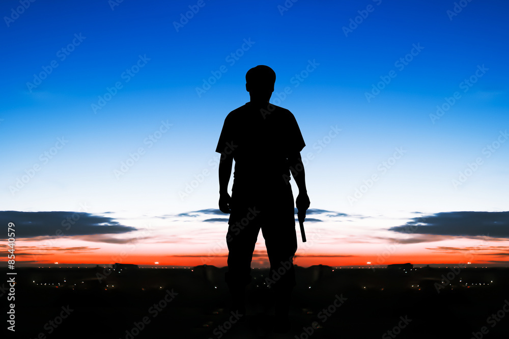 silhouette rear of man standing hand hold holding gun revolvers on sunrise and full moon on the sky in the city background