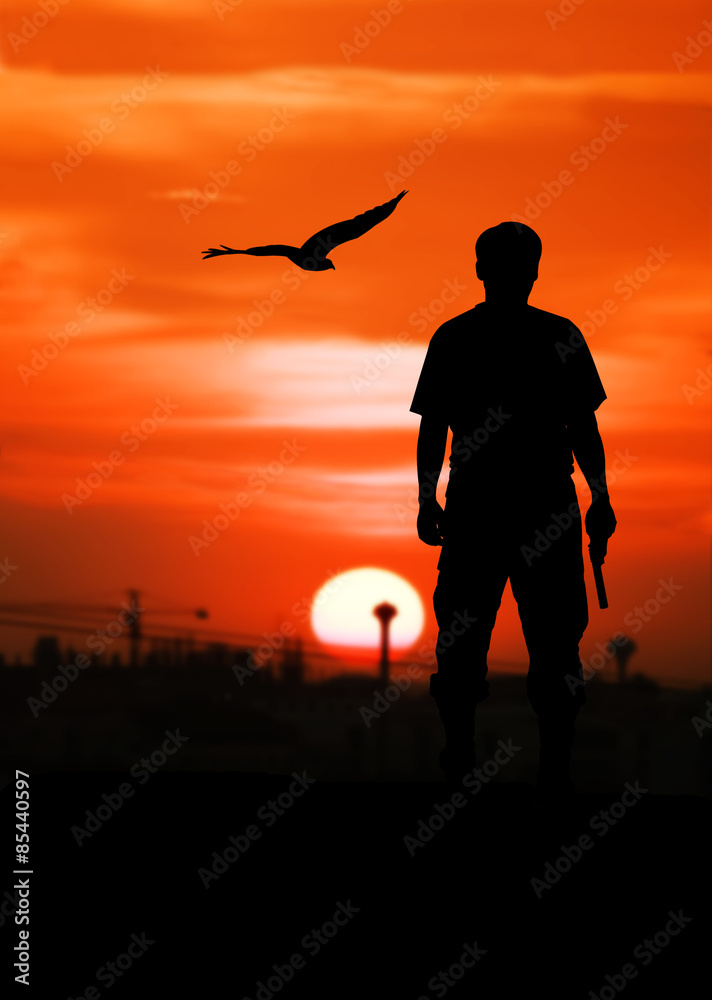 silhouette rear of man standing hand holding gun revolvers on sunset in the city background