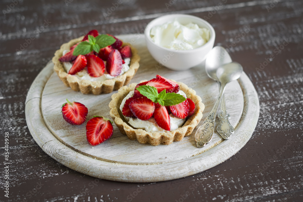 tartlets with cream cheese and strawberries on a light wooden background tartlets with cream cheese and strawberries on a light wooden background
