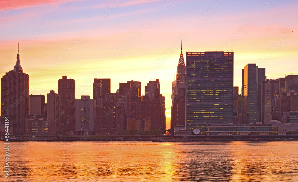 Fototapeta premium New York City, Manhattan famous landmark buildings skyline in downtown at beautiful colorful sunset with reflections