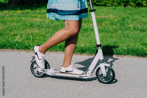 Legs of young woman on kick scooter