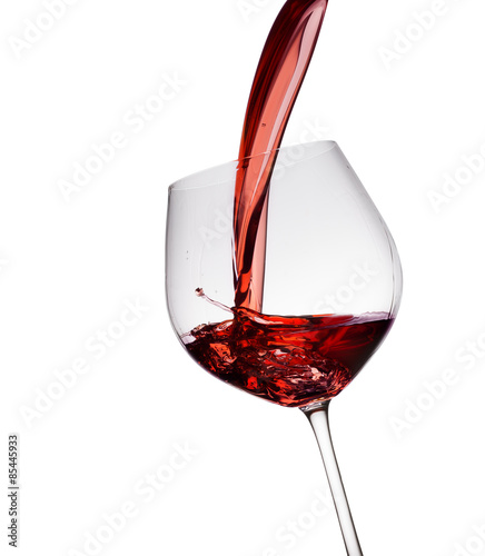 Red wine poured in a glass isolated on white