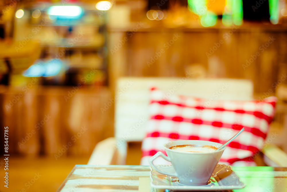 Cup of coffee on a wooden table with red pillow in cafe Cup of coffee on a wooden table with red pillow in cafe