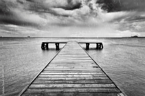 Old jetty, pier on the sea. Black and white, rain.