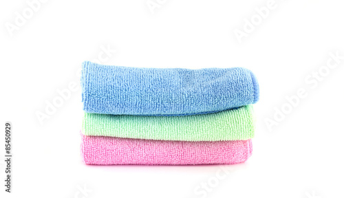 Pink, blue and green towels roll horizontally on a white backgro