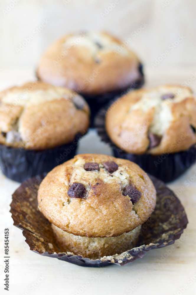 Four chocolate chip muffins on wooden tabletop
