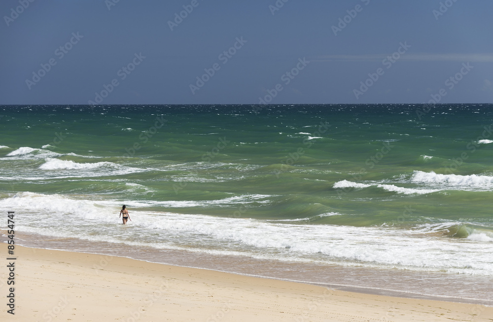 Young girl enjoying the waves of the Atlantic Ocean in Algarve, Portugal, Europe