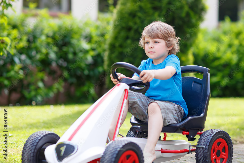 Active little boy having fun and driving toy race car Active little boy having fun and driving toy race car
