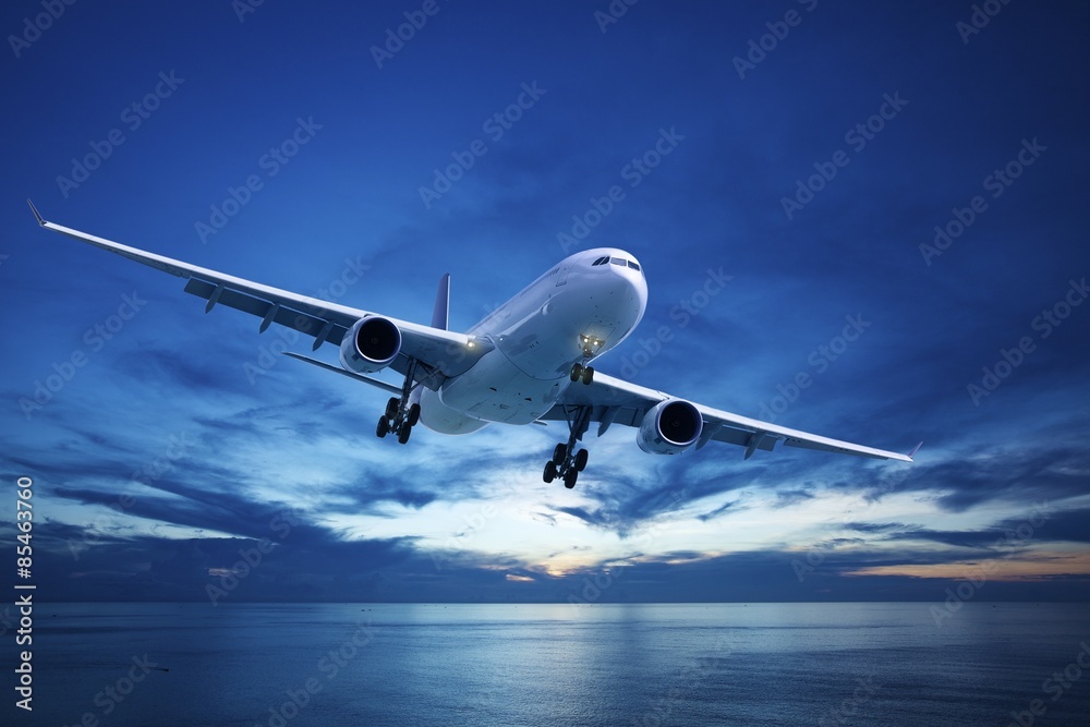 Obraz premium Samolot odrzutowy nad morzem o zmierzchu