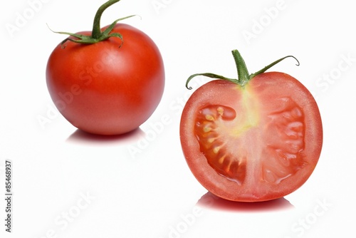 In primo piano pomodoro rosso tagliato a metà isolato e su sfondo bianco