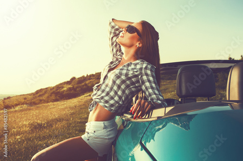 Attractive young woman posing leaning on convertible car © djile