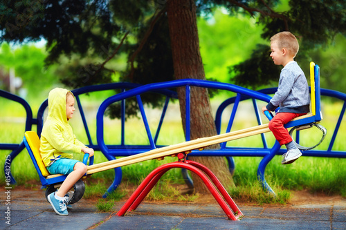 cute kids having fun on seesaw at playground photo