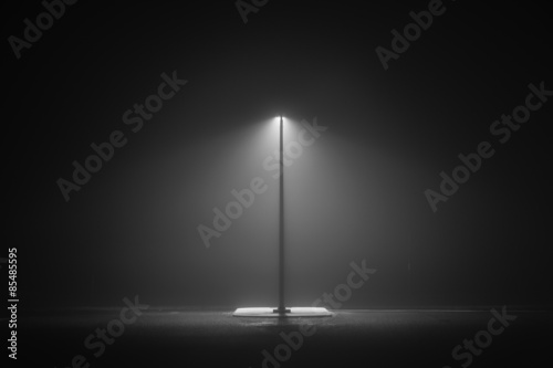 Darkness.  Lonely light at the entrance to a park long a highway in a cold and misty night photo