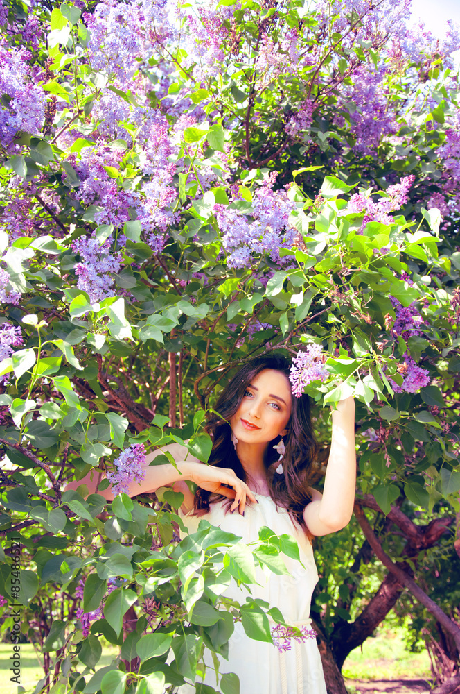 Woman with long brown hair in lilac bushes