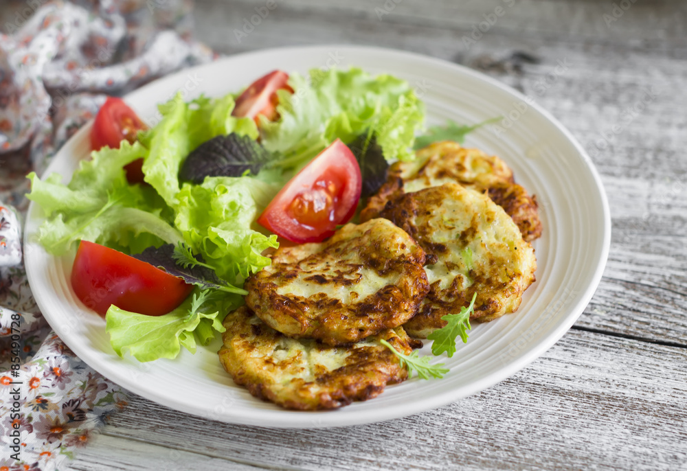 zucchini pancakes and fresh vegetable salad on white plate zucchini pancakes and fresh vegetable salad on white plate
