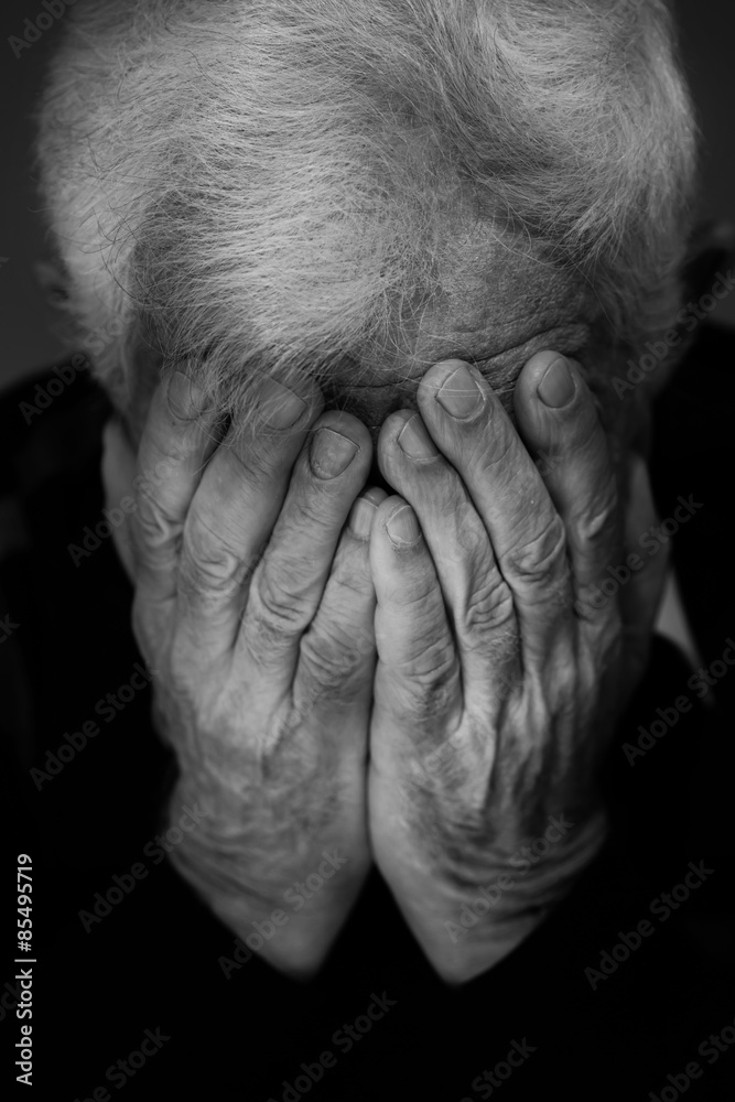 Hands covering face of old man