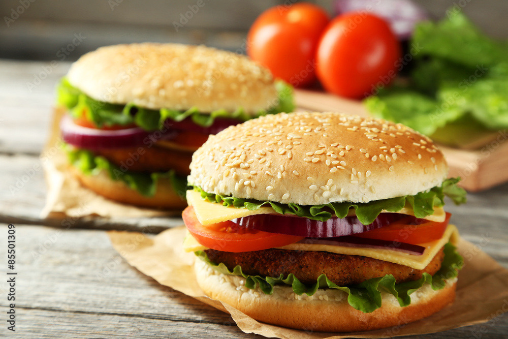 Fresh burgers on grey wooden background